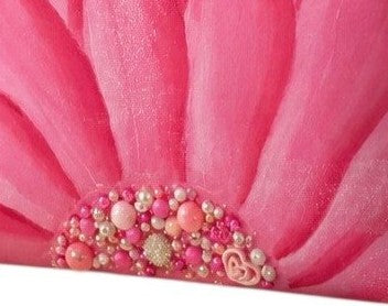 close up of Hand-painted rope handle beach tote featuring a bold pink floral design with jeweled embellishments at the flower center, accented with natural jute trim and oversized cream rope handles against a neutral background.