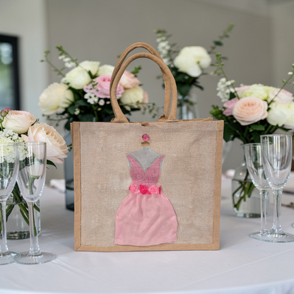 Hand-painted jute tote bag featuring a blush pink bridesmaid dress with floral details on a natural canvas background