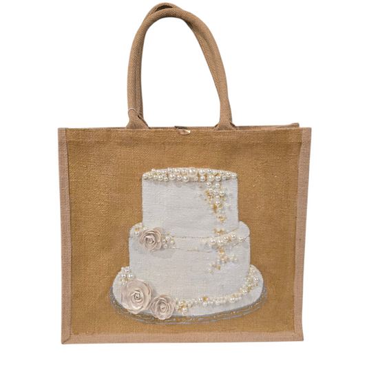 Hand-painted jute tote bag featuring an elegant white wedding cake with pearl and floral details on a natural canvas background