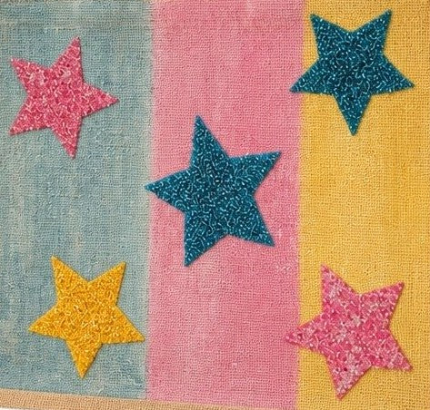 close up of Colorful hand-painted jute tote bag featuring pastel blue, pink, and yellow panels accented with glittery star designs in teal, pink, and gold. The structured tote has natural woven handles and a bright, playful aesthetic inspired by fun artisan fashion accessories.